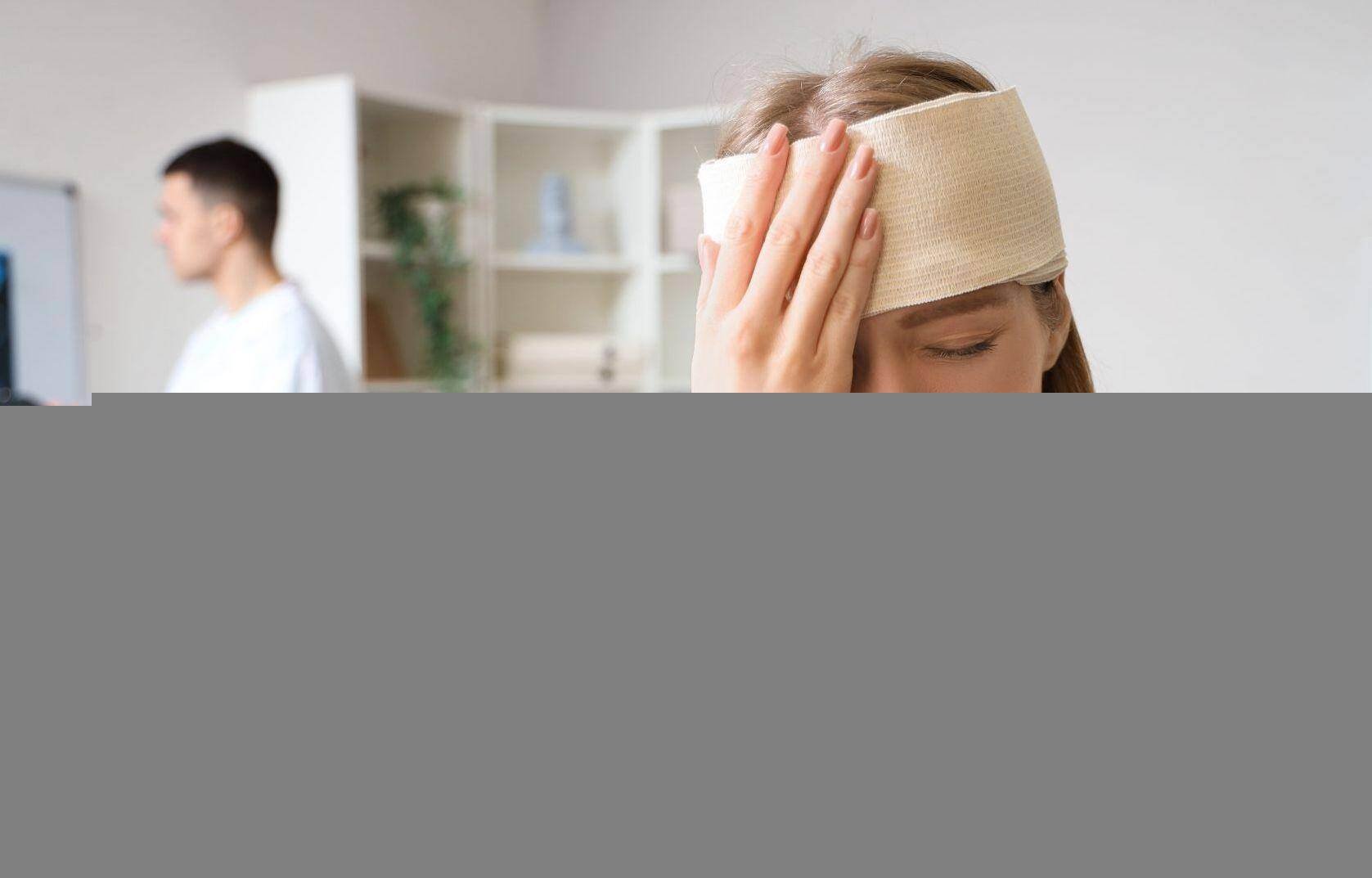 A woman with a damp rag on her head soothing a head injury next to a neurologist in Mobile, Alabama
